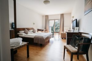 Helles und modernes Hotelzimmer in der Südsteiermark mit Doppelbett, Sitzbereich und TV.