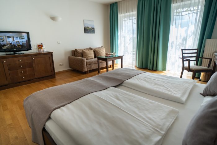 Helles und modernes Hotelzimmer Weinland (barrierefrei) in der Südsteiermark mit Doppelbett, Sitzbereich und TV.