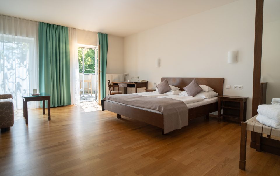 Helles und modernes Hotelzimmer in der Steiermark mit Doppelbett, Sitzbereich und TV.