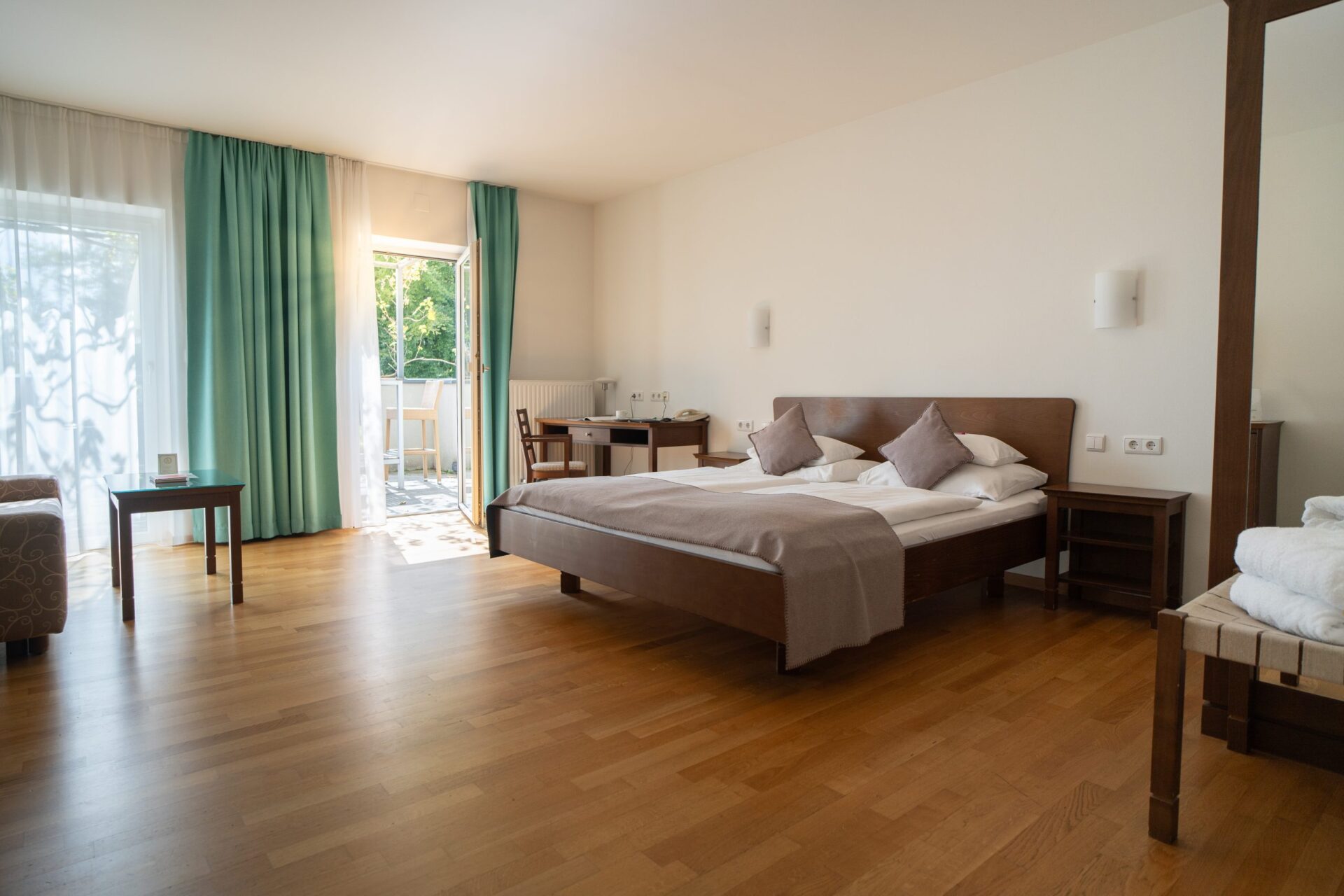 Helles und modernes Hotelzimmer in der Steiermark mit Doppelbett, Sitzbereich und TV.