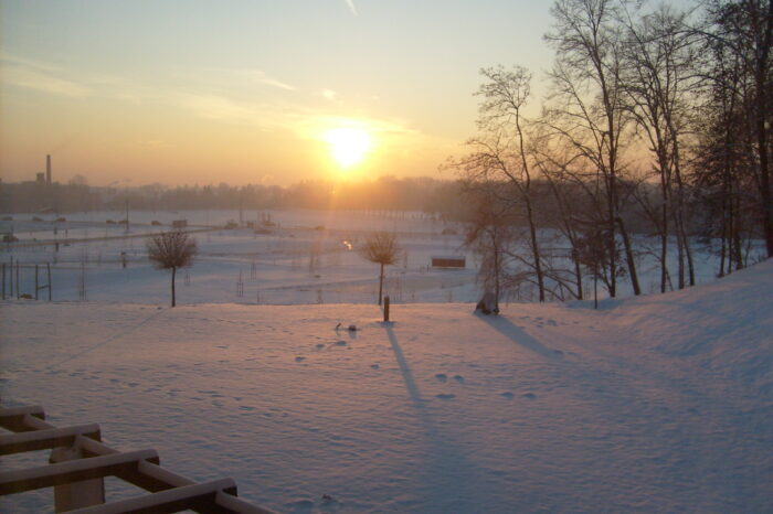 Die Abendsonne wirft ein rotes Licht auf die tief verschneite Liegewiese.